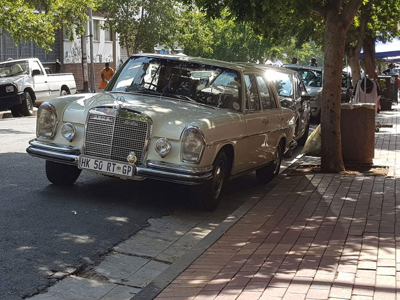 Een klassieke witte Mercedes geparkeerd aan de stoep.